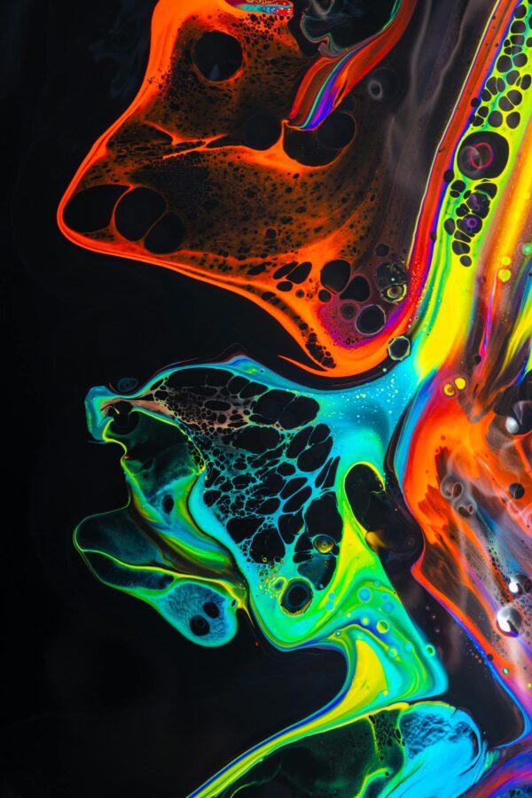 Colorful mix of neon paints swirling on black surface